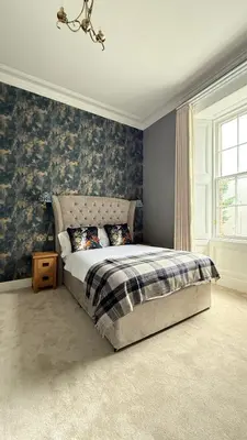 a bedroom with a bed with blue wallpaper at Armadillo Guest House- Adults Only in Edinburgh