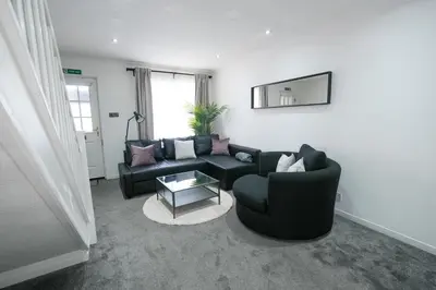 a living room with a black couch and a table at Modern 2 Bedroom Platinum Pad Glasgow City in Glasgow