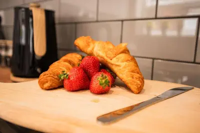 a cutting board with strawberries and croissants and a knife at 4 Bed Sheffield home in Moffat