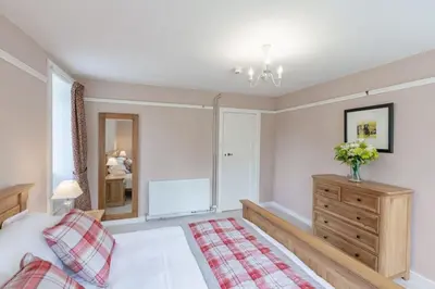 a bedroom with a bed and a dresser and a mirror at Lonan Country House and Gardens in Taynuilt
