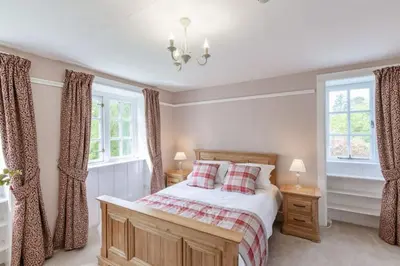 a bedroom with a bed and two windows at Lonan Country House and Gardens in Taynuilt