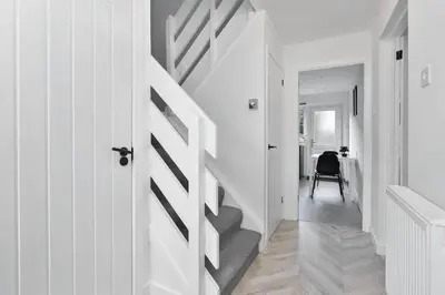 a hallway with white walls and stairs with a door at Livingston Retreat 4bed Home Wi-Fi Parking in Uphall