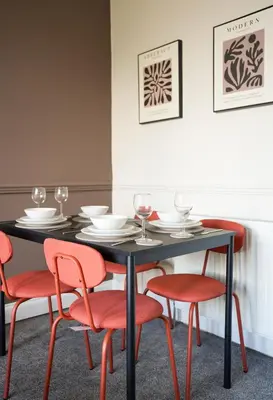 a black table with red chairs and wine glasses at Neilston Apartment in Paisley