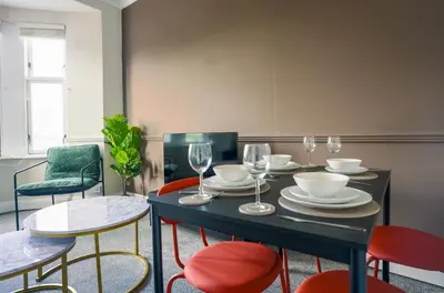 a dining room with a table with chairs and wine glasses at Neilston Apartment in Paisley