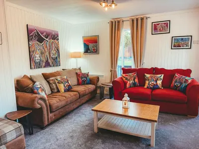 a living room with a couch and a table at Highland Coo Lodge in Dunoon