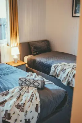 a room with two beds and a table with a lamp at Highland Coo Lodge in Dunoon