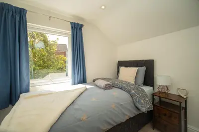 a bedroom with a bed with blue curtains and a window at Spacious 3 Bedroom home in Ascot, Sleeps 5, Parking in Moffat