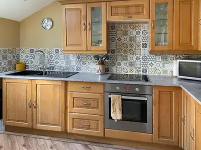 a kitchen with wooden cabinets and a stove top oven at Monawilline Cottage in Lamlash
