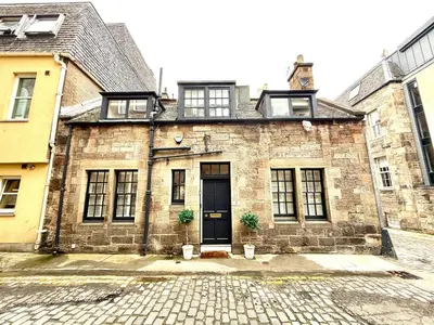 an old brick building with a black door at Historic Mews House 2BR in Edinburgh City Centre in Edinburgh