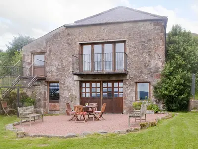 a stone house with a table and chairs in front of it at Townhead Mill in Dumfries