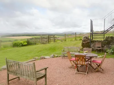 a patio with a table and chairs with a view of a field at Townhead Mill in Dumfries