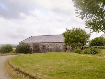 an old stone barn on a grassy field next to a road at Townhead Mill in Dumfries