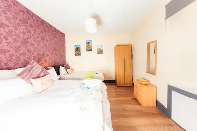 a bedroom with two beds and a pink wall at Cosy Central Apartment by the Meadows 4 in Edinburgh