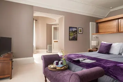 a bedroom with a purple bed and a chair at Quarter House in Peebles