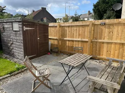 a patio with two chairs and a wooden fence at The Wee Flat in Uphall