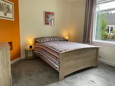 a bedroom with a bed with two lamps and a window at The Wee Flat in Uphall