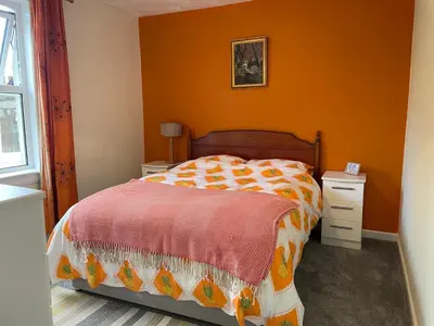 a bedroom with a bed with an orange wall at The Wee Flat in Uphall