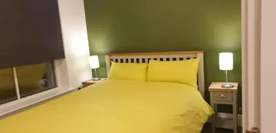 a bedroom with a yellow bed with a green wall at Oatlands Oasis-FREE PARKING-2 Minutes from M74 in Glasgow