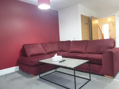a red couch in a living room with a table at Oatlands Oasis-FREE PARKING-2 Minutes from M74 in Glasgow