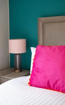 a bed with a pink pillow and a lamp at California House in Falkirk