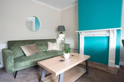 a living room with a green couch and a table at California House in Falkirk