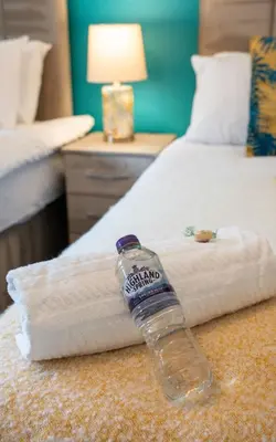 a bottle of water sitting on top of a bed at Whitburn house in Whitburn