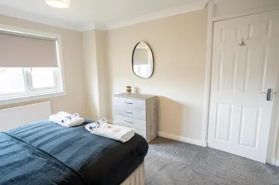 a bedroom with a bed and a mirror and a dresser at Whitburn house in Whitburn