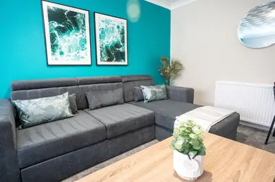 a living room with a gray couch and a blue wall at Whitburn house in Whitburn