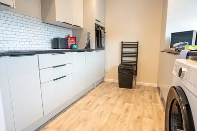 a kitchen with white cabinets and a washer and dryer at Whitburn house in Whitburn