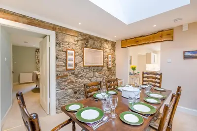 a dining room with a table and chairs and a stone wall at 3 Bed in Comrie oc-e33307 in Comrie