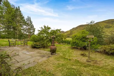 a garden with a table and a vase in the grass at 3 Bed in Comrie oc-e33307 in Comrie
