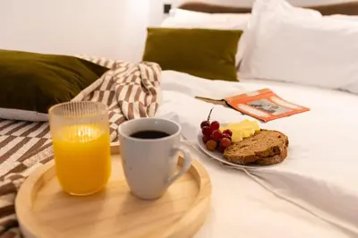 a tray with a cup of orange juice and a plate of food at Botanic House - 3BR Home - Private Parking in Glasgow