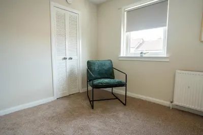 a green chair sitting in a room with a window at 2 BDR House At Caledonia Luxe Stays Short Lets & Serviced Accommodation Hamilton in Hamilton