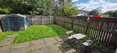 a yard with two chairs and a fence at 3 bedrooms home away from home in Uphall