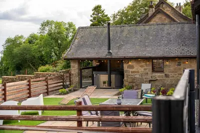a stone cottage with a table and chairs in a yard at The Cottage at Barraston Farm in Glasgow