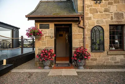 a building with two vases with flowers on the door at The Cottage at Barraston Farm in Glasgow