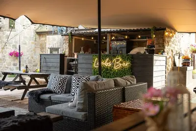 a patio with couches and a table and a bar at Barraston Farm in Glasgow