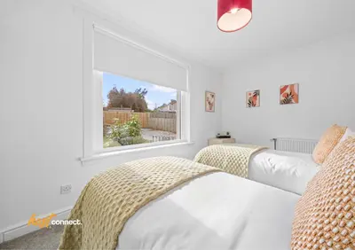 two beds in a bedroom with a window at 2 Bed Sleeps 4 with Private Parking in Airdrie in Airdrie