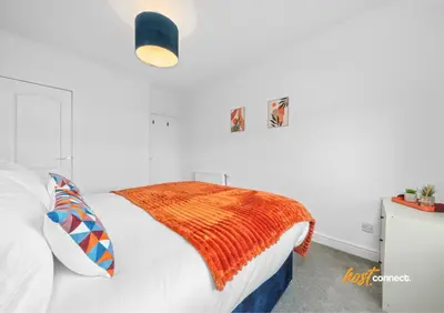 a bedroom with a bed with an orange blanket on it at 2 Bed Sleeps 4 with Private Parking in Airdrie in Airdrie
