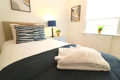 a bedroom with a bed with towels on it at Signature - Oak House in Coatbridge