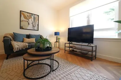 a living room with a couch and a flat screen tv at Signature - Oak House in Coatbridge
