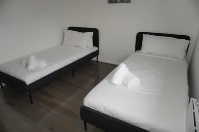 two beds in a room with white sheets and white pillows at Glasgow Riverview Apartment in Glasgow