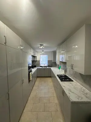a large kitchen with white cabinets and a tile floor at Fairholme Gardens House in Moffat