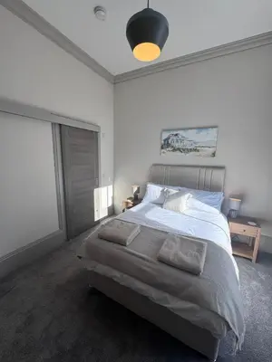 a white bedroom with a large bed and a large window at Taobh na Mara - Macaulay Letting in Helensburgh