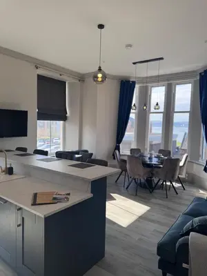 a living room with a kitchen and a dining room at Taobh na Mara - Macaulay Letting in Helensburgh