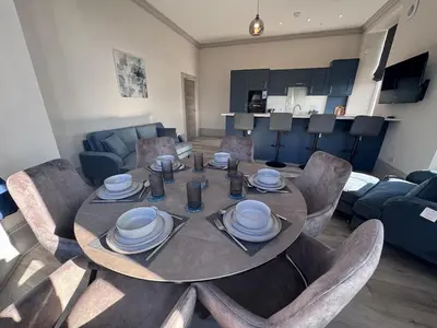 a dining table and chairs in a living room at Taobh na Mara - Macaulay Letting in Helensburgh