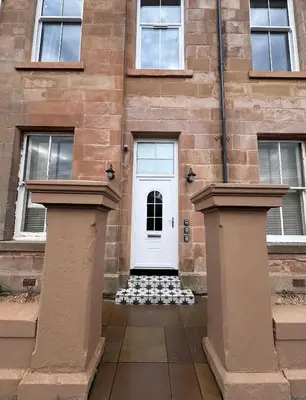 a white door on a brick building at Taobh na Mara - Macaulay Letting in Helensburgh