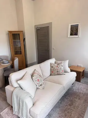 a white couch with pillows in a living room at The Comet - Macaulay Letting in Helensburgh
