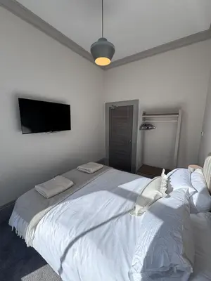 a bedroom with a large white bed with a flat screen tv at The Comet - Macaulay Letting in Helensburgh
