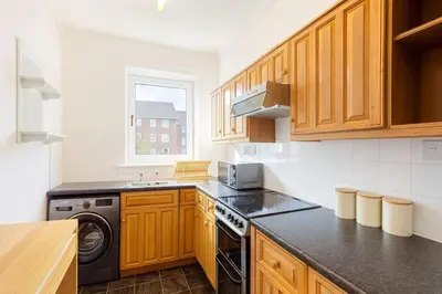 a kitchen with wooden cabinets and a stove top oven at Bright & Spacious 2 Bedroom Flat in Edinburgh